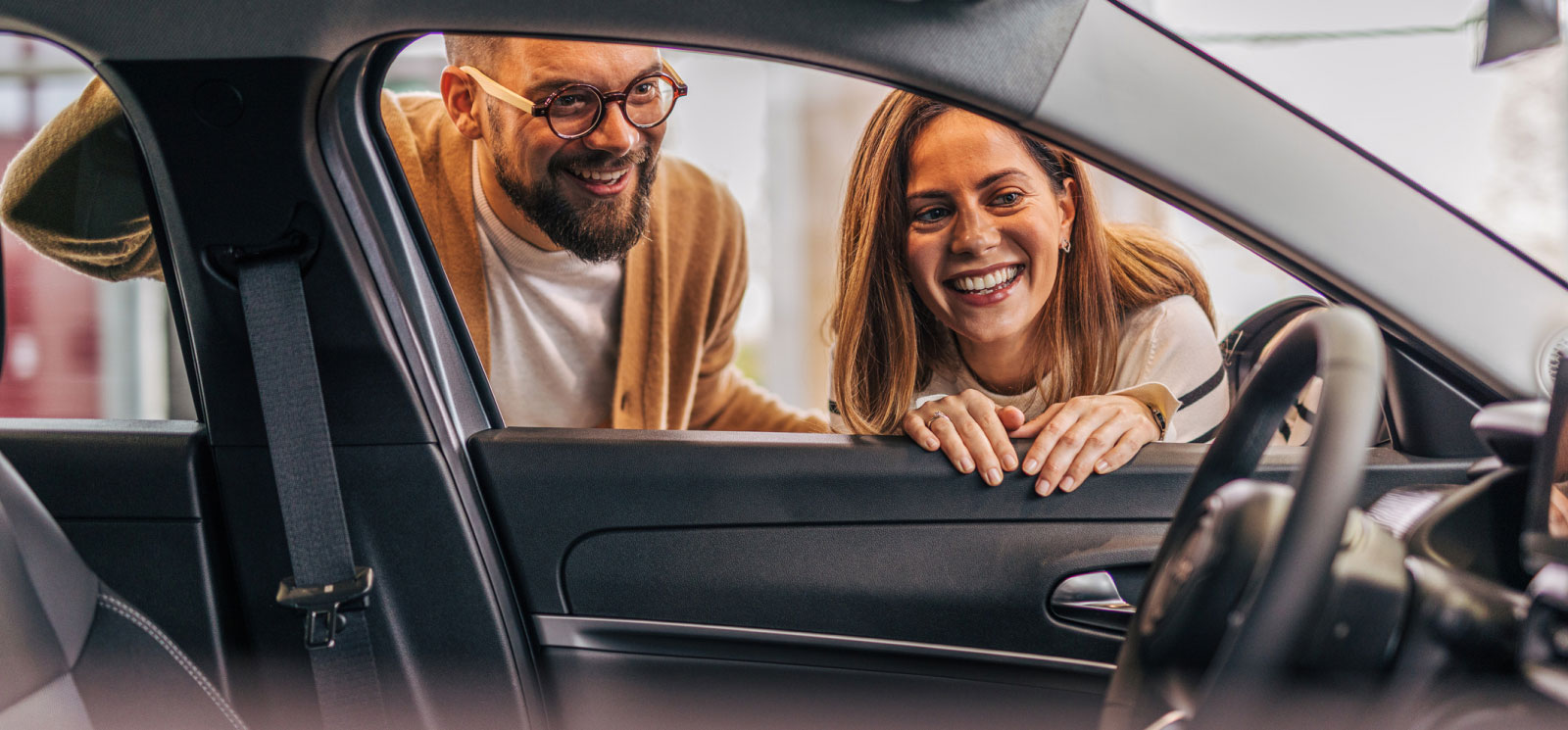 two adults looking at the interior of a car