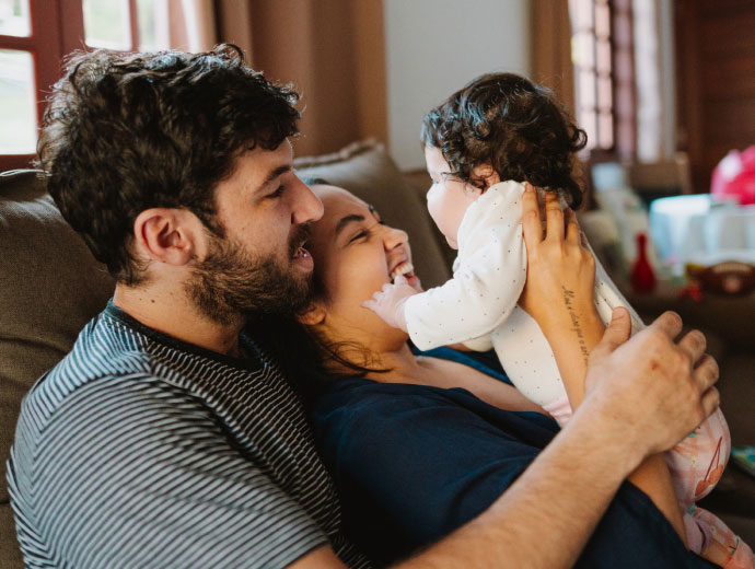 young family with a newborn sitting on a couch