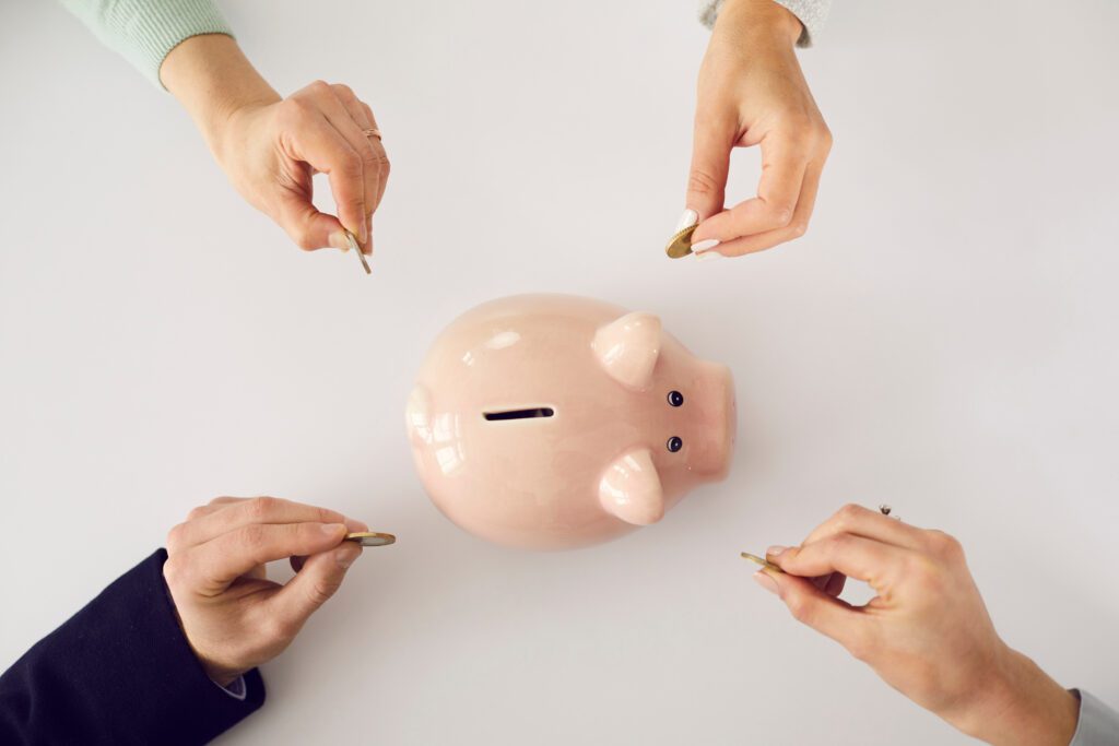 Hands placing coins into a piggy bank, representing saving money and financial planning
